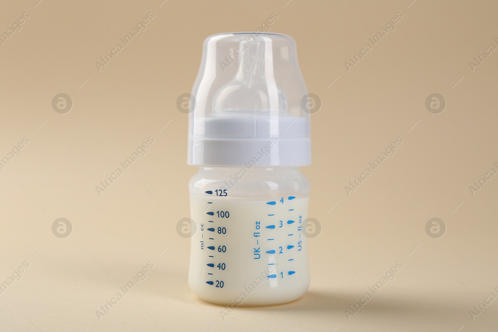 Photo of Feeding bottle with milk on beige background