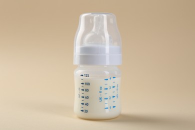 Feeding bottle with milk on beige background