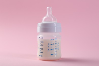 Feeding bottle with milk on pink background