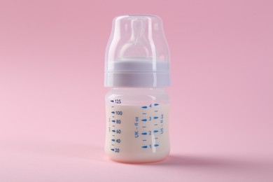 Feeding bottle with milk on pink background