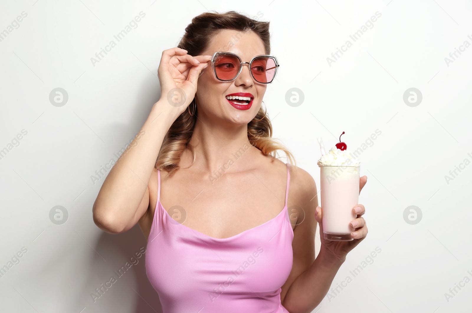 Photo of Happy woman with milk shake on light background. Pin-up vibe portrait