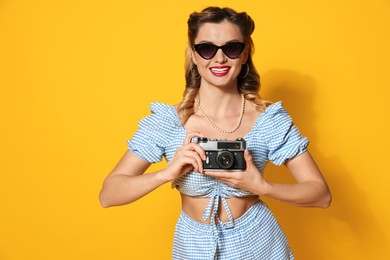 Happy pin-up woman with camera on orange background