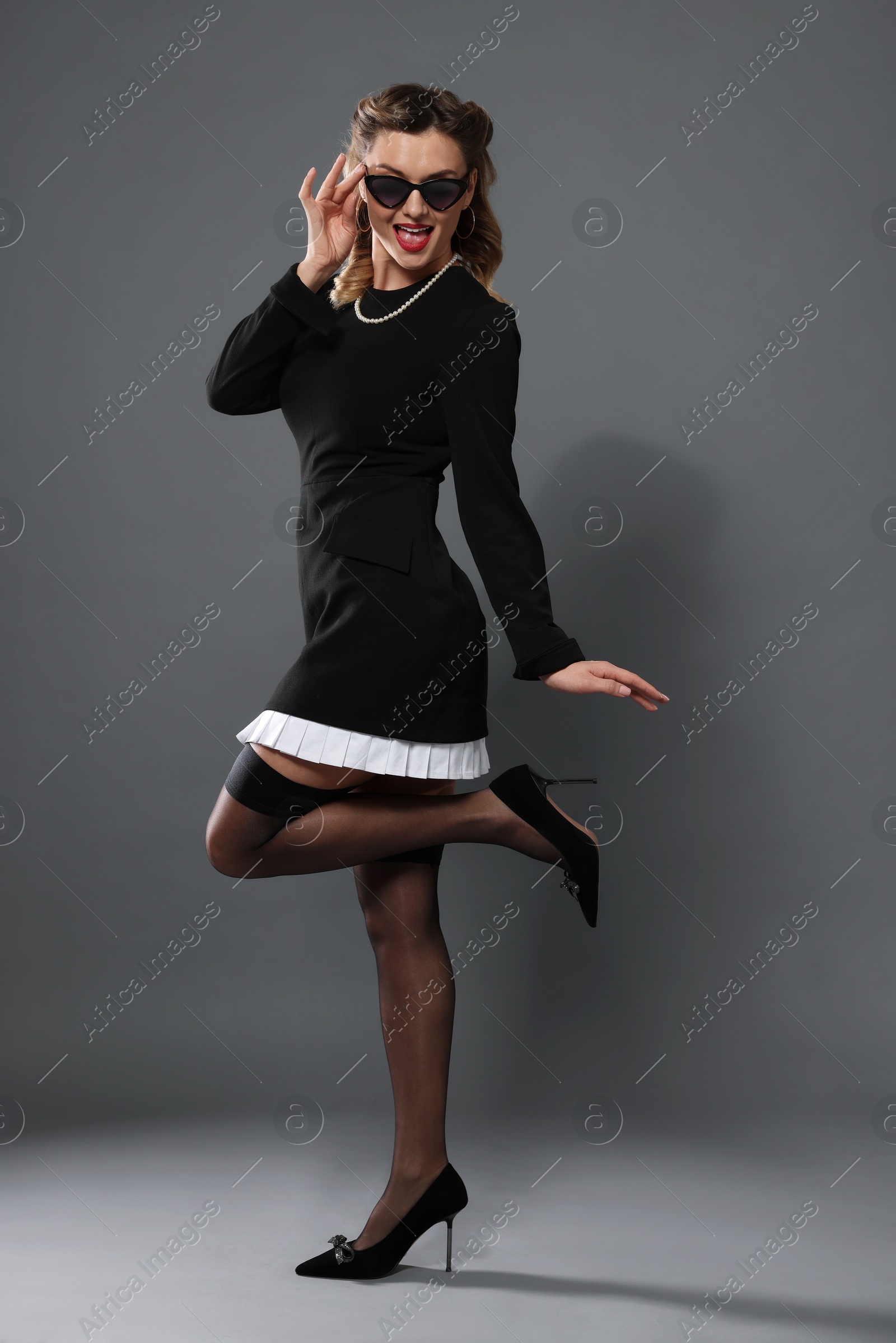 Photo of Beautiful pin-up woman posing on grey background