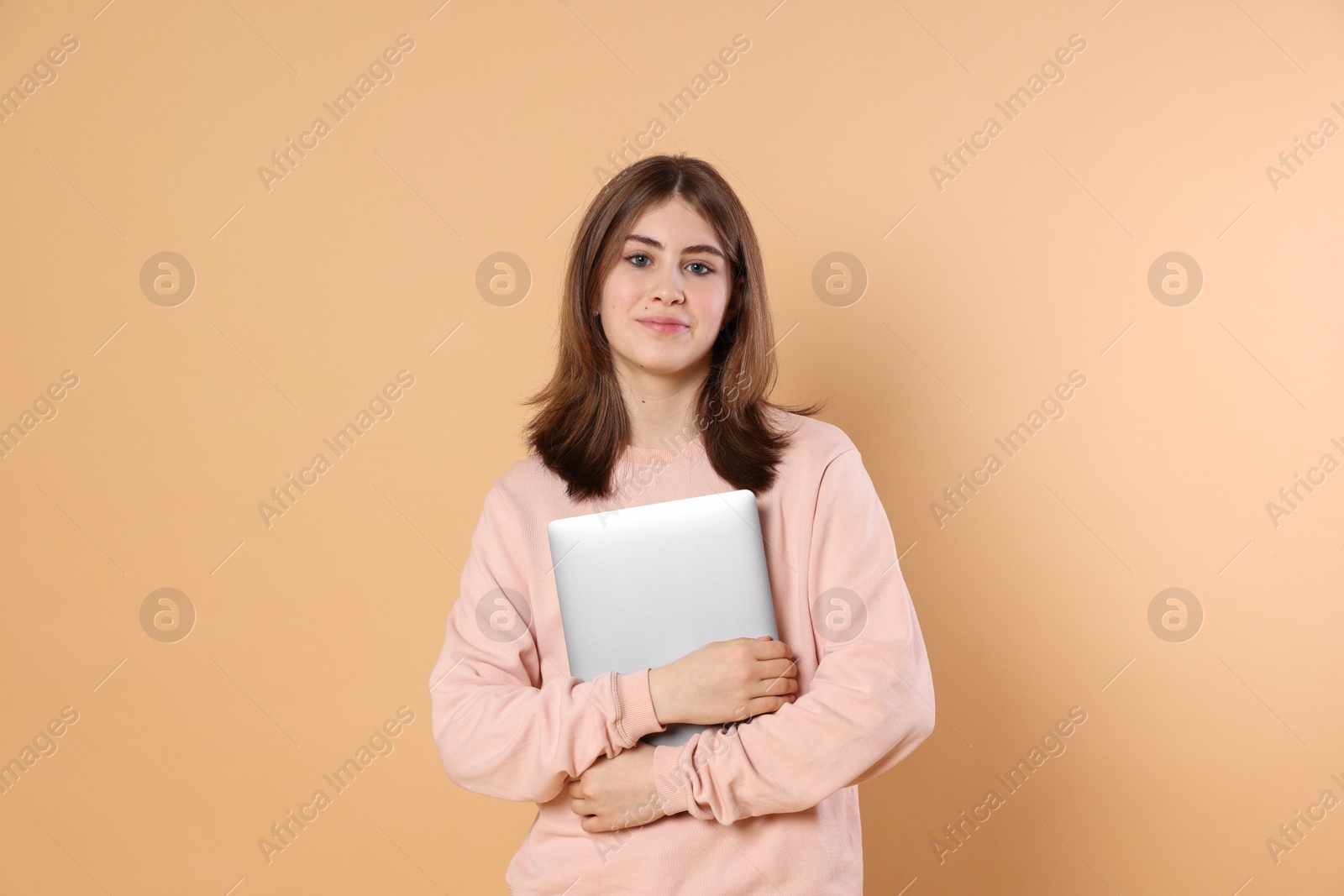 Photo of Portrait of teenage girl with laptop on beige background