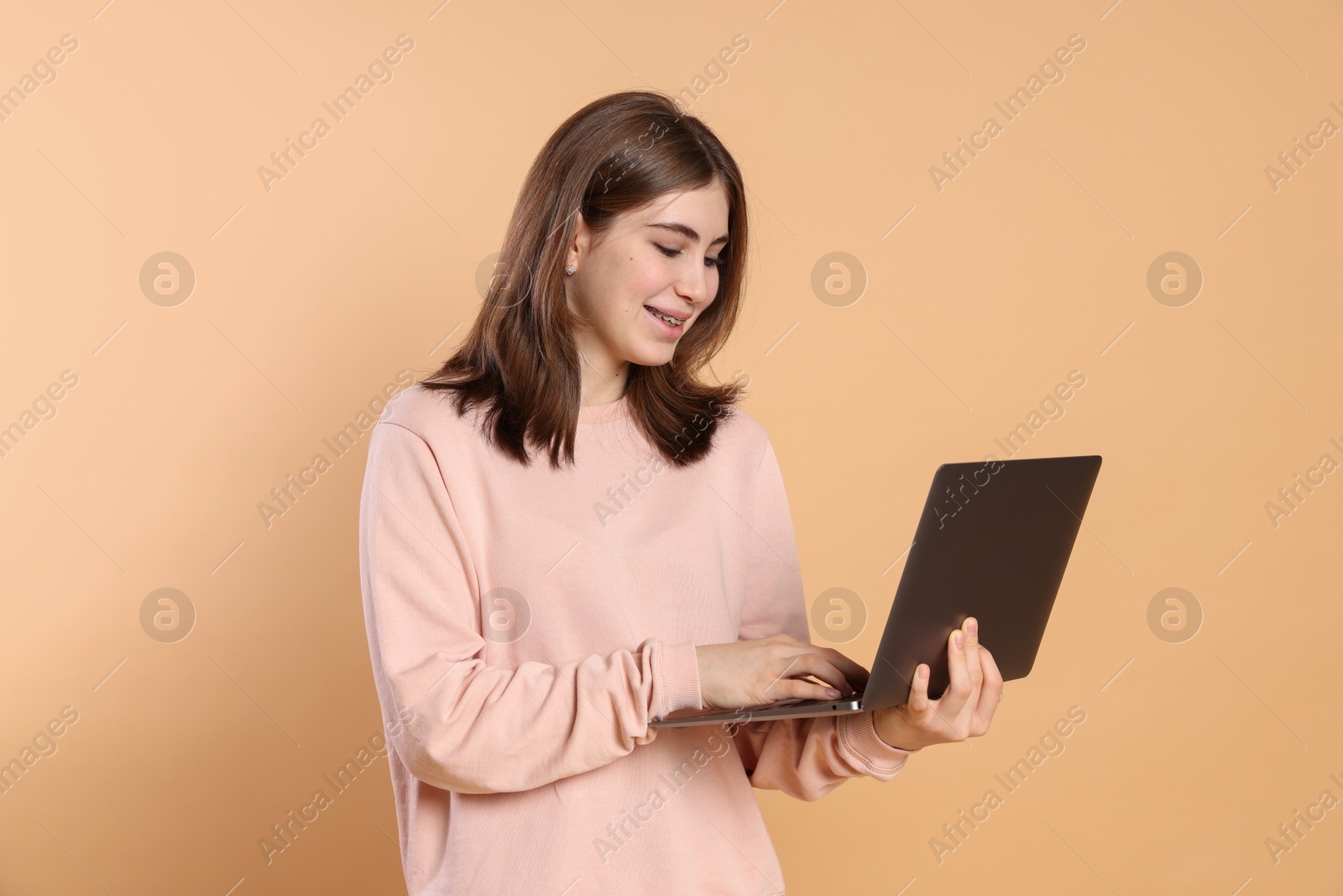 Photo of Portrait of teenage girl using laptop on beige background