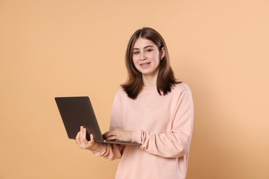 Photo of Portrait of teenage girl using laptop on beige background