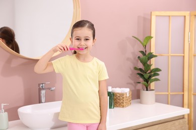 Cute girl brushing her teeth in bathroom