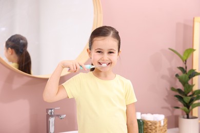 Photo of Cute girl brushing her teeth in bathroom