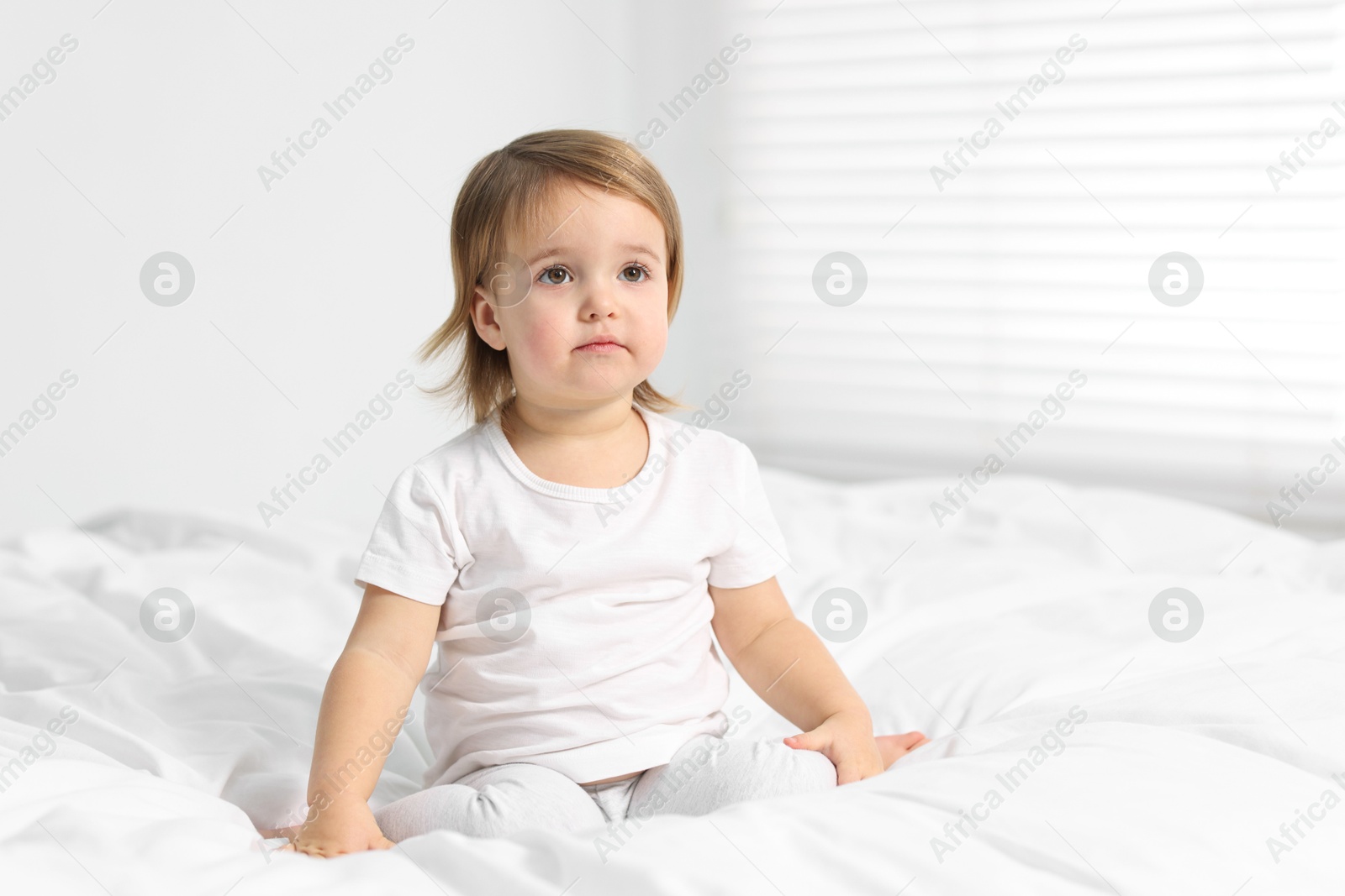 Photo of Cute little baby girl on bed at home. Space for text