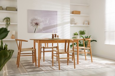 Photo of Stylish room with wooden table, chairs and houseplants. Interior design