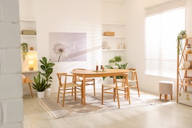 Photo of Stylish room with wooden table, chairs and houseplants. Interior design