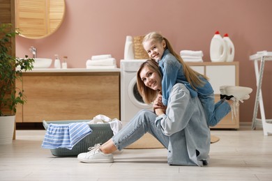 Photo of Mother and daughter having fun while doing laundry together at home