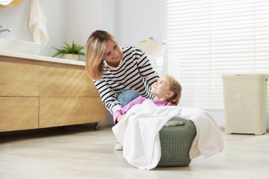 Photo of Mother and daughter having fun while doing laundry together at home