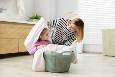 Little girl and her mom doing laundry together at home