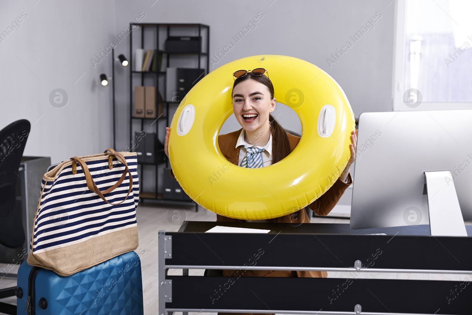 Photo of Businesswoman with inflatable ring and sunglasses at workplace in office