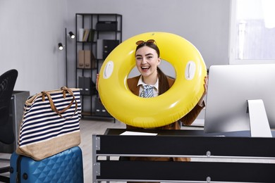 Photo of Businesswoman with inflatable ring and sunglasses at workplace in office