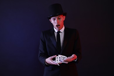 Photo of Illusionist showing trick with playing cards on dark background