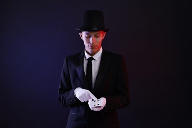 Photo of Illusionist showing trick with playing cards on dark background