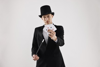 Photo of Illusionist pointing magic wand on playing cards against white background