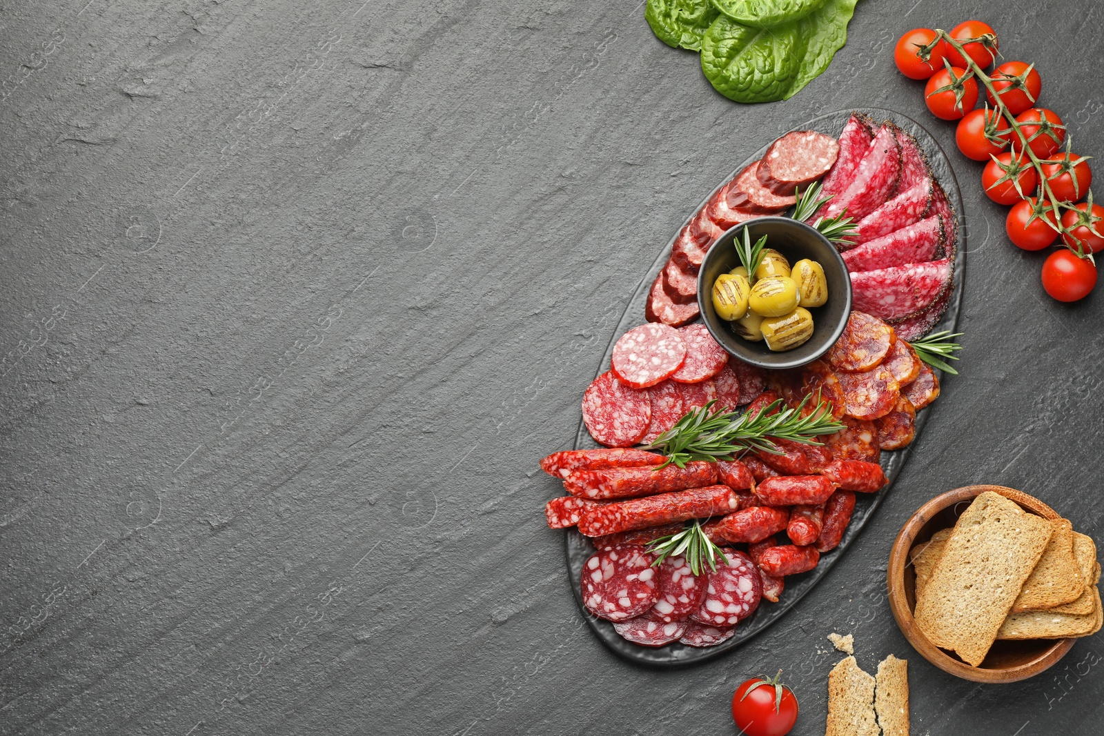 Photo of Different smoked sausages and other snacks on black table, flat lay. Space for text