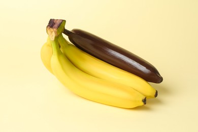 Photo of Stop racism. Bunch of yellow bananas with dark one on beige background