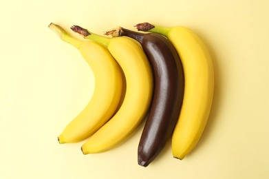 Photo of Stop racism. One dark banana among yellow ones on beige background, flat lay