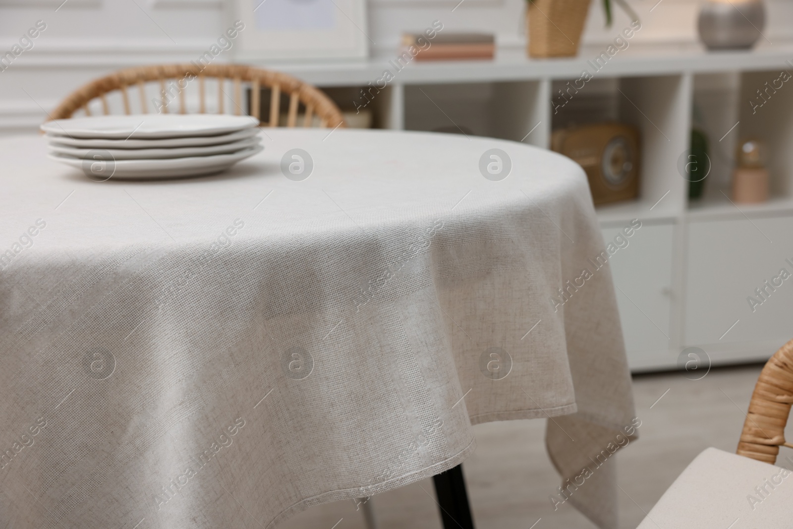 Photo of Table with white tablecloth and plates in room, closeup