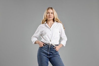 Photo of Beautiful young woman in stylish jeans on grey background