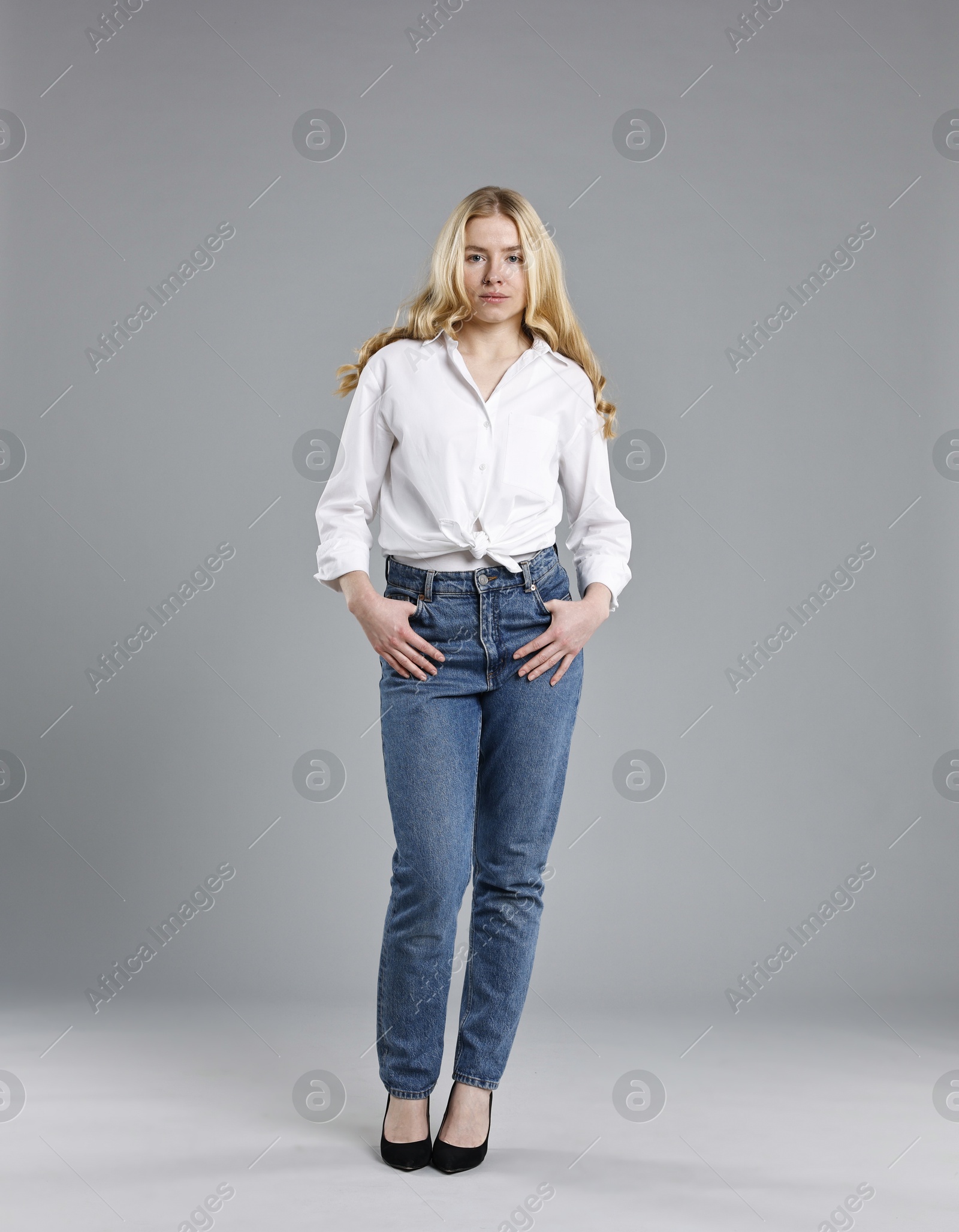 Photo of Beautiful young woman in stylish jeans on grey background