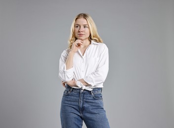 Beautiful young woman in stylish jeans on grey background