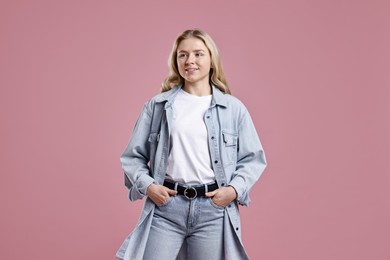 Photo of Smiling woman in stylish jeans on pink background