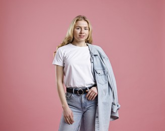 Photo of Smiling woman in stylish jeans on pink background