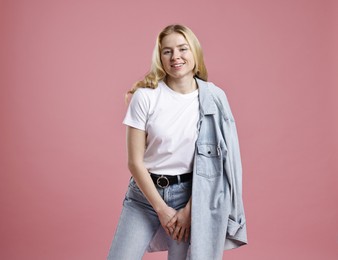 Smiling woman in stylish jeans on pink background