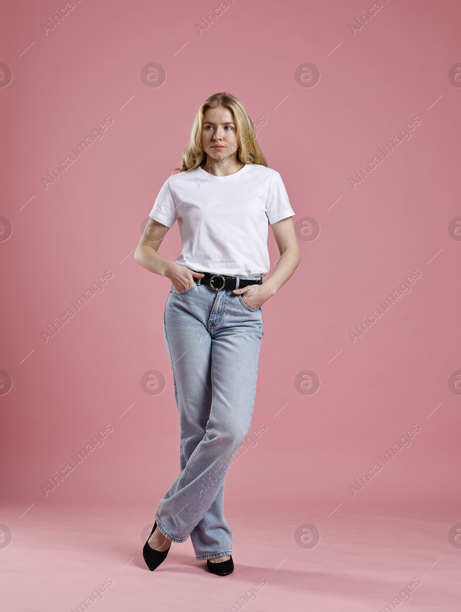 Photo of Beautiful young woman in stylish jeans on pink background