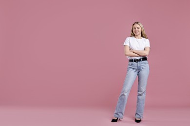 Photo of Smiling woman in stylish jeans on pink background. Space for text