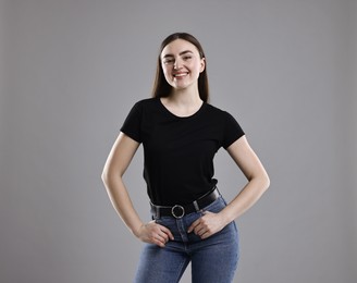 Photo of Smiling woman in stylish jeans on grey background