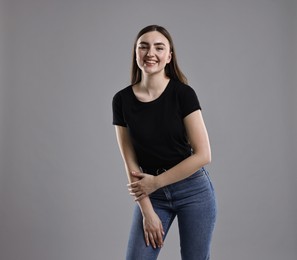 Photo of Smiling woman in stylish jeans on grey background