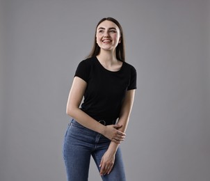 Photo of Smiling woman in stylish jeans on grey background