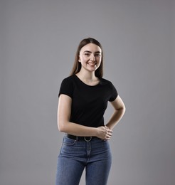 Photo of Smiling woman in stylish jeans on grey background