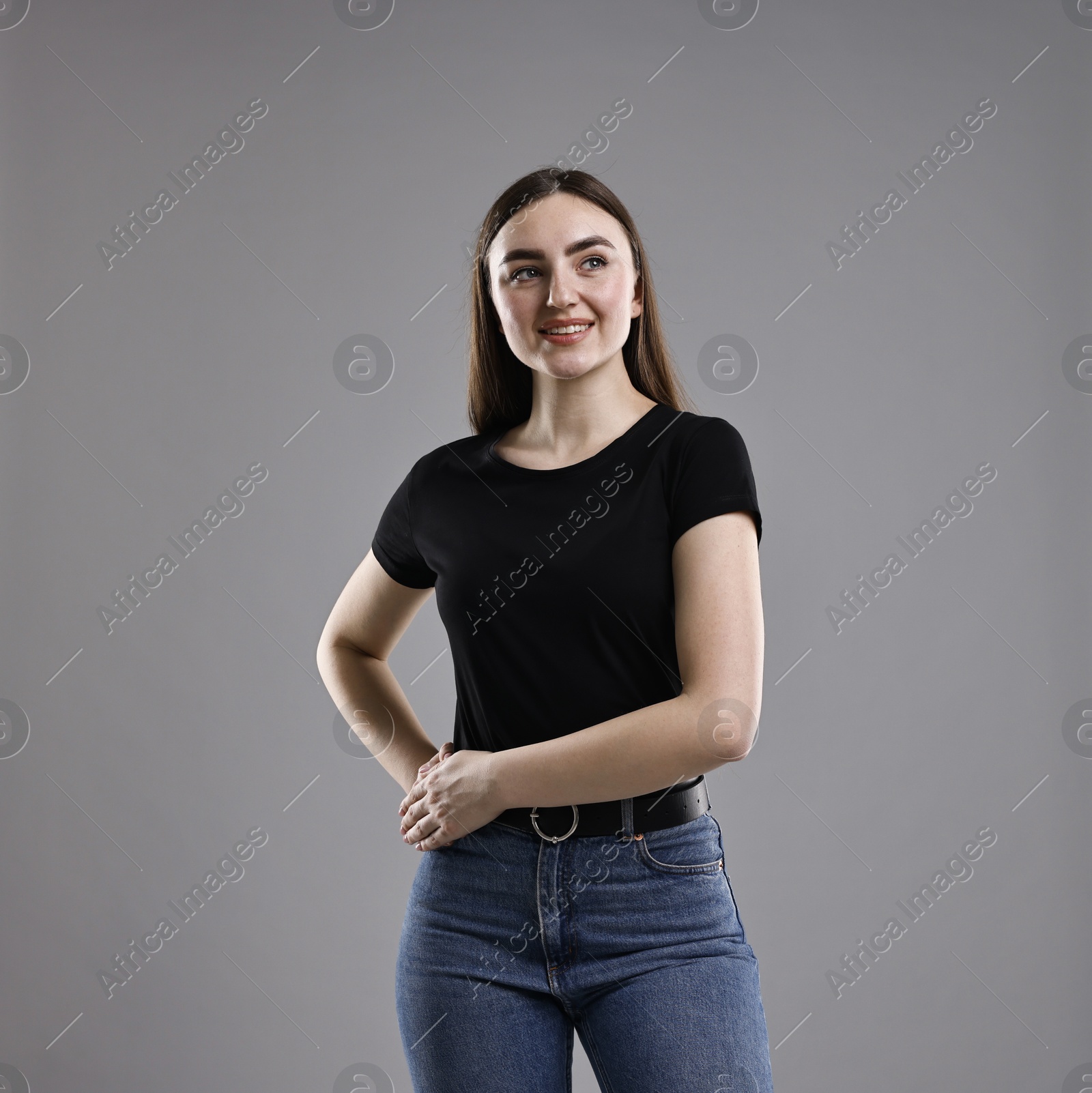 Photo of Smiling woman in stylish jeans on grey background