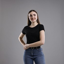 Photo of Smiling woman in stylish jeans on grey background