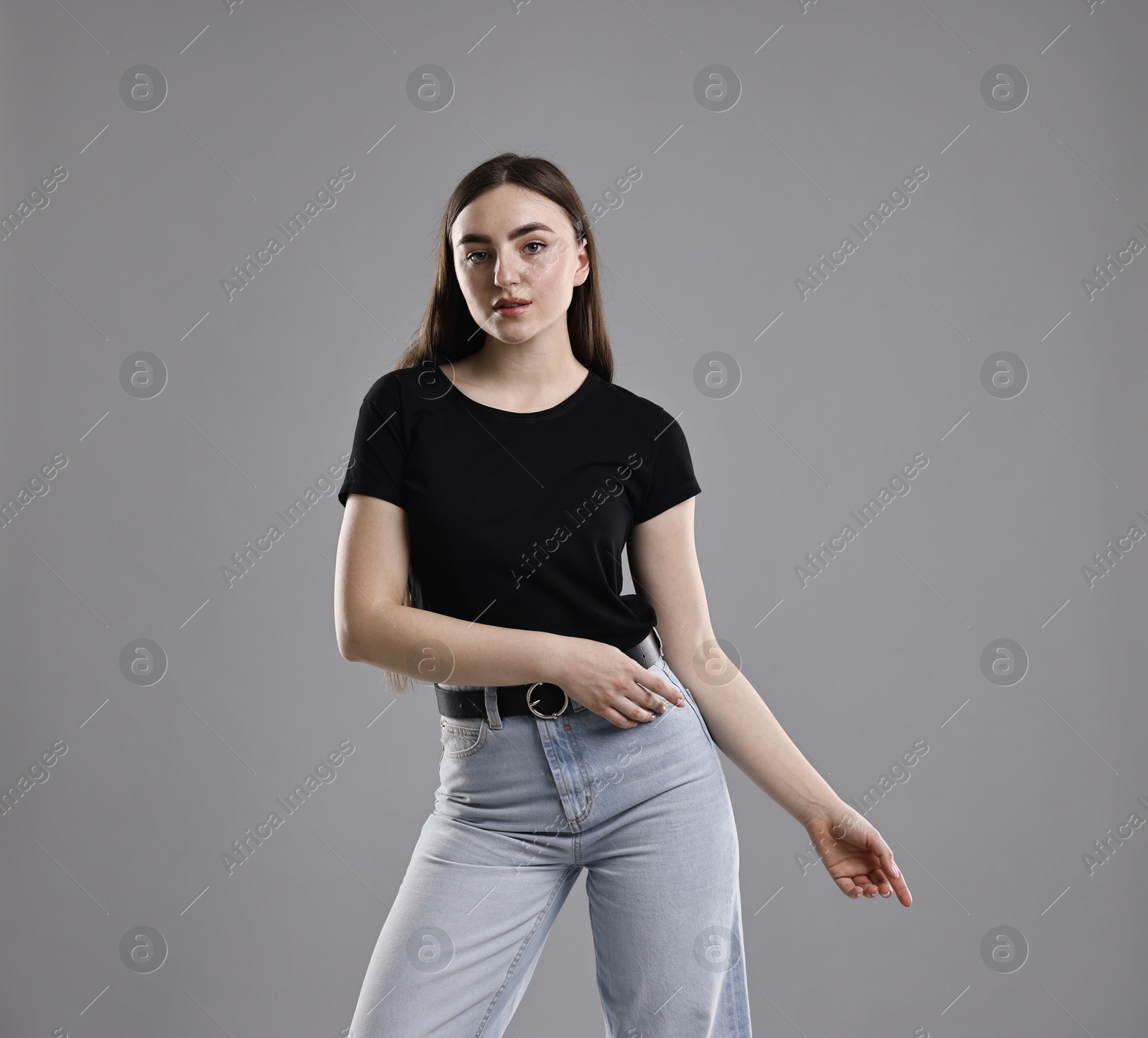 Photo of Beautiful young woman in stylish jeans on grey background