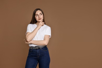 Photo of Woman in stylish jeans on brown background. Space for text