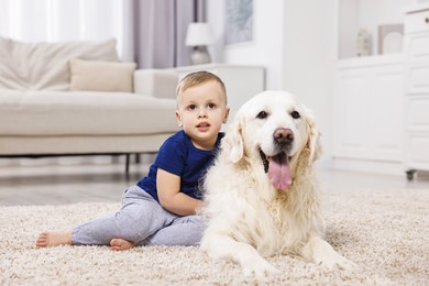 Photo of Little boy with cute dog on carpet at home