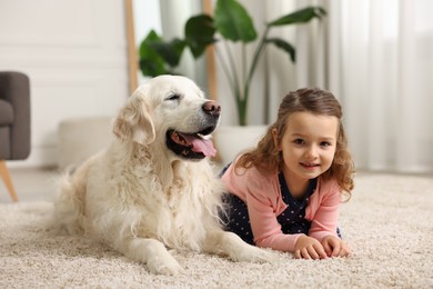 Little girl with cute dog on carpet at home