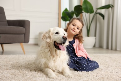 Photo of Little girl with cute dog on carpet at home