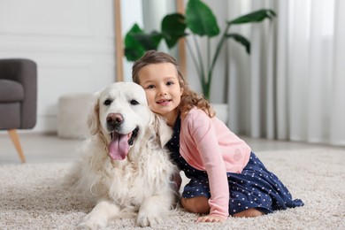 Little girl with cute dog on carpet at home