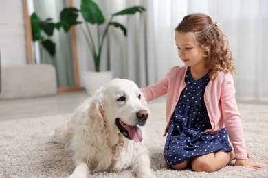 Little girl with cute dog on carpet at home