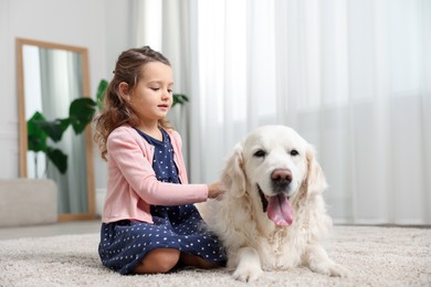 Photo of Little girl with cute dog on carpet at home