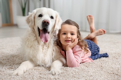 Little girl with cute dog on carpet at home